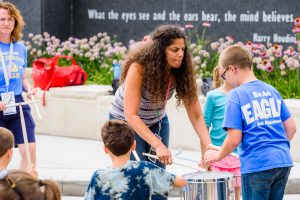 Leila Ramagopal Pertl teaches a young festival attendee during a drum workshop. This workshop is part of the Music Education Team's work during the festival. Photo: Graham Washatka
